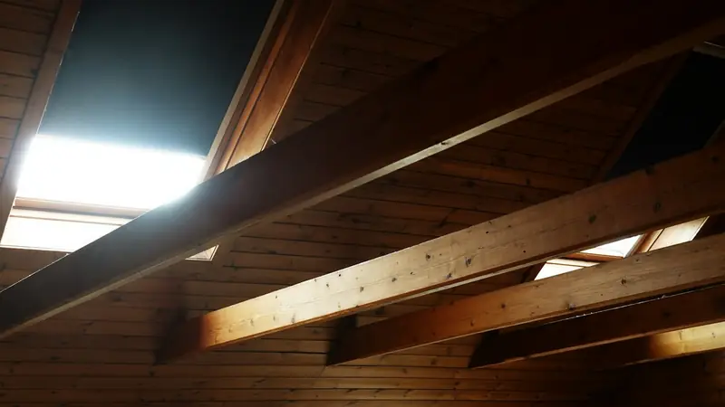 Holzbalken unter einem Dachboden mit Licht von oben