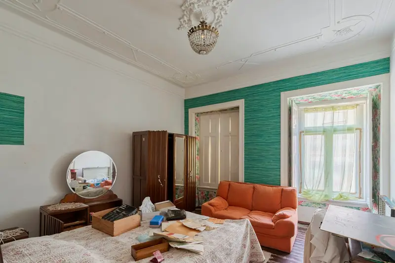 Zugestelltes Zimmer mit Sofa, Kartons und alten Möbeln