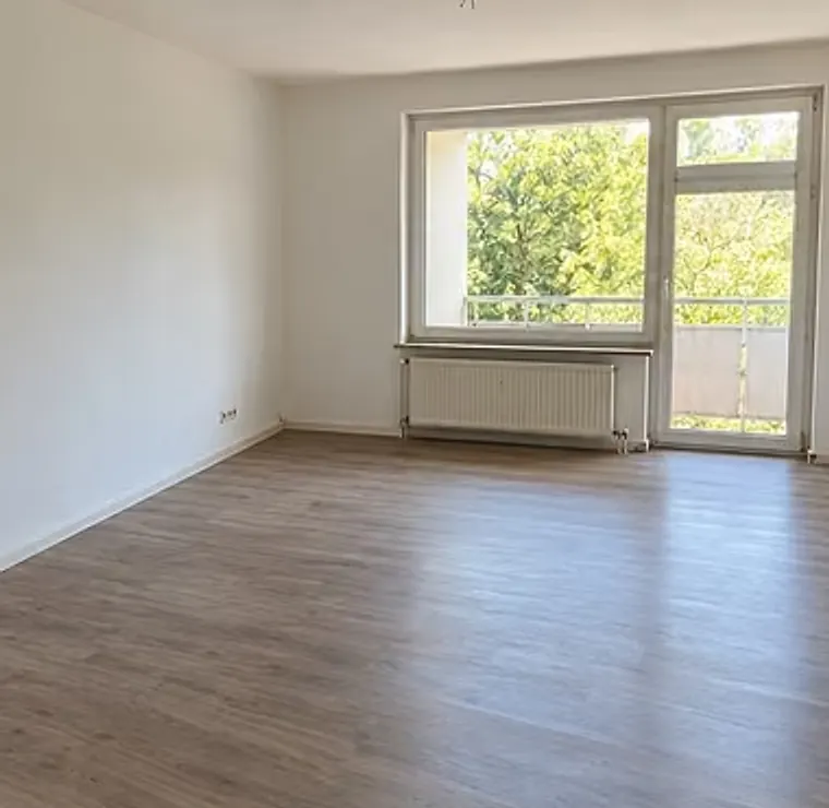 Dasselbe Wohnzimmer nach der Räumung, leer, mit hellem Boden und Blick ins Grüne